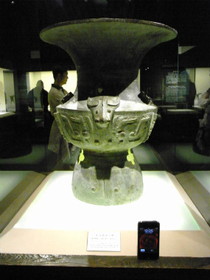 Tomato Juice‘s China Travel とまとじゅーす的中国旅行、上海博物館・青銅器展。商代後期、1300～1100年頃の牛首獣面尊という青銅器。iPhone 3Gと大きさ比較